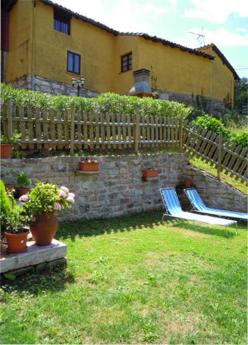 Jardín con tumbonas y fachada de piedra de los apartamentos